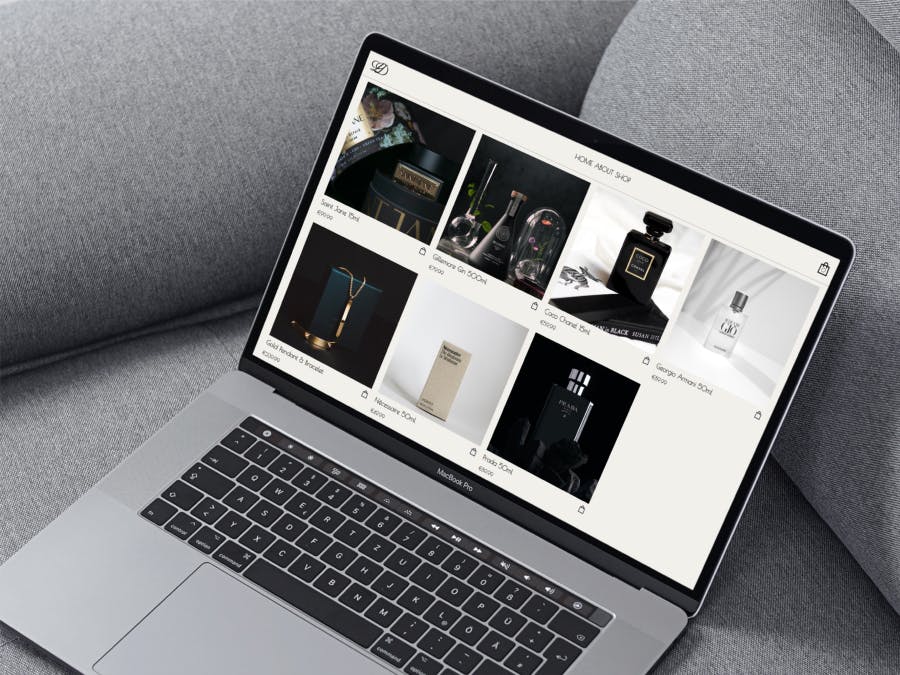 A luxury e-commerce website on a Macbook resting on a grey couch