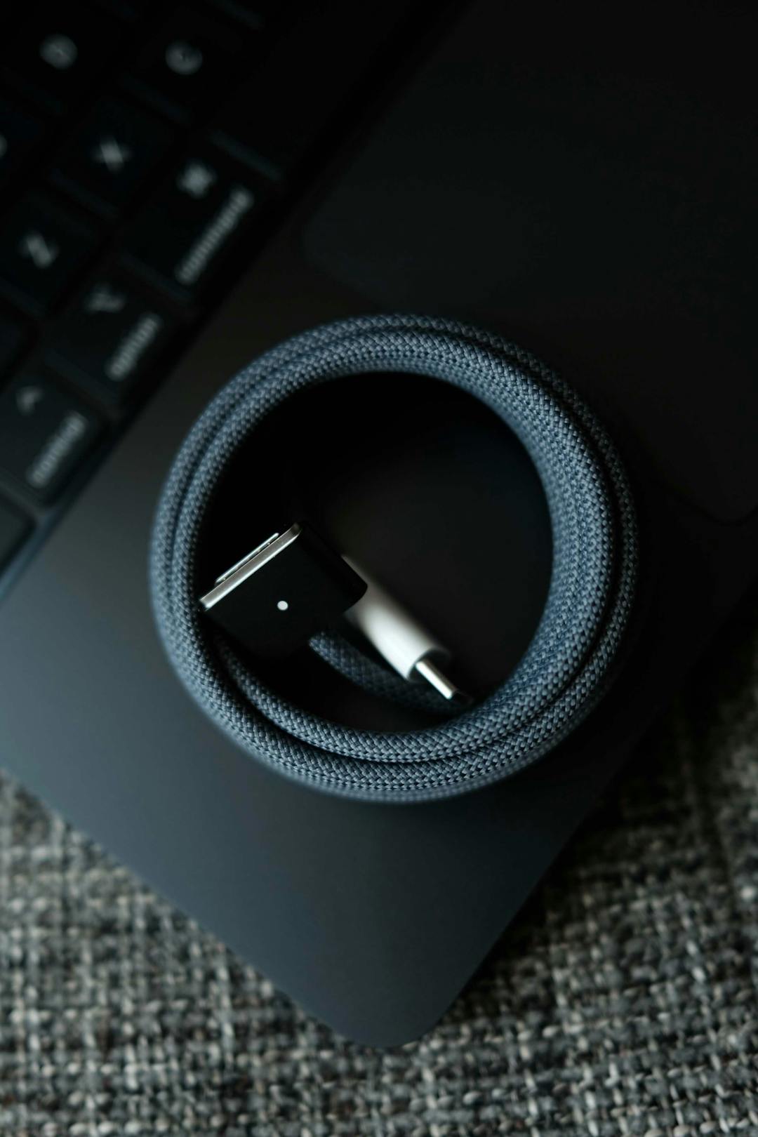 A fibre-weaved cord, wrapped into a circle on top of a laptop keyboard