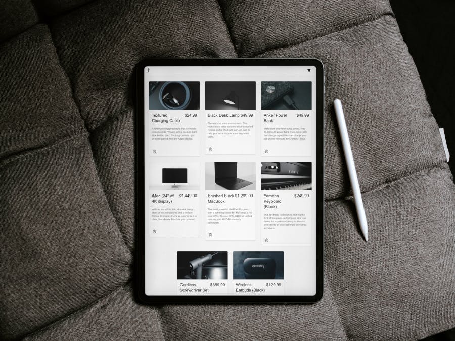 An iPad resting on a cushion with an ecommerce site open on the screen and a stylus pen next to it